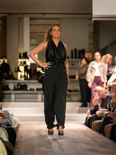 Zwarte top met blote schouders en een wijde broek op pumps