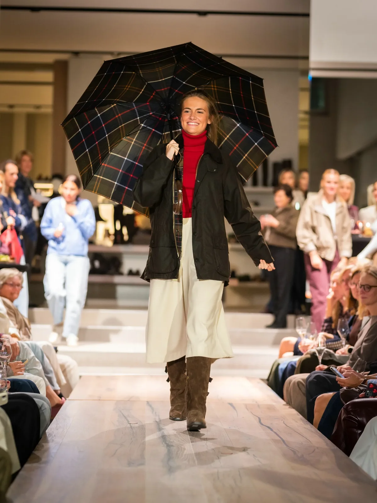 Groene regenjas met rode trui, beige wijde short en suede cognac boots