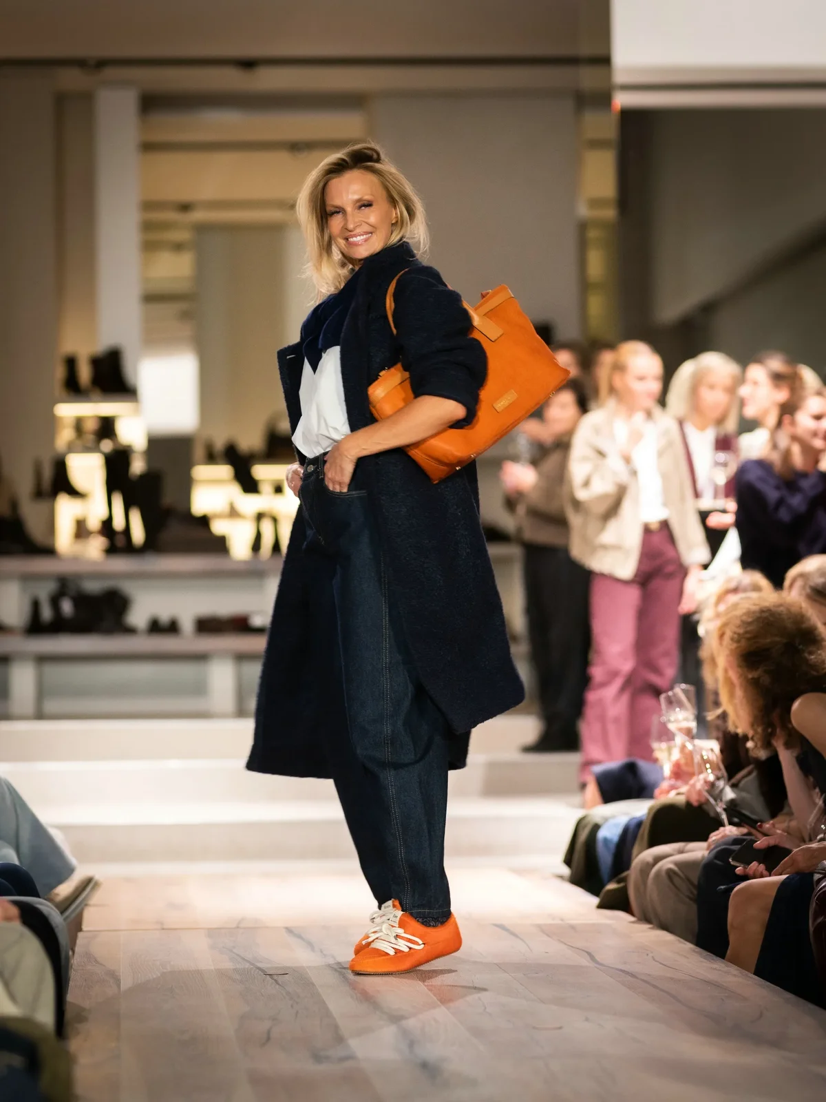 Blauwe jas met off-white blouse, blauwe broek en oranje sneakers