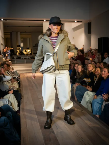 Kaki jas met bordeaux T-shirt, off-white broek en bruine boots